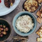 A variety of Mediterranean appetizers featuring hummus, olives, and grilled vegetables set on a rustic table.